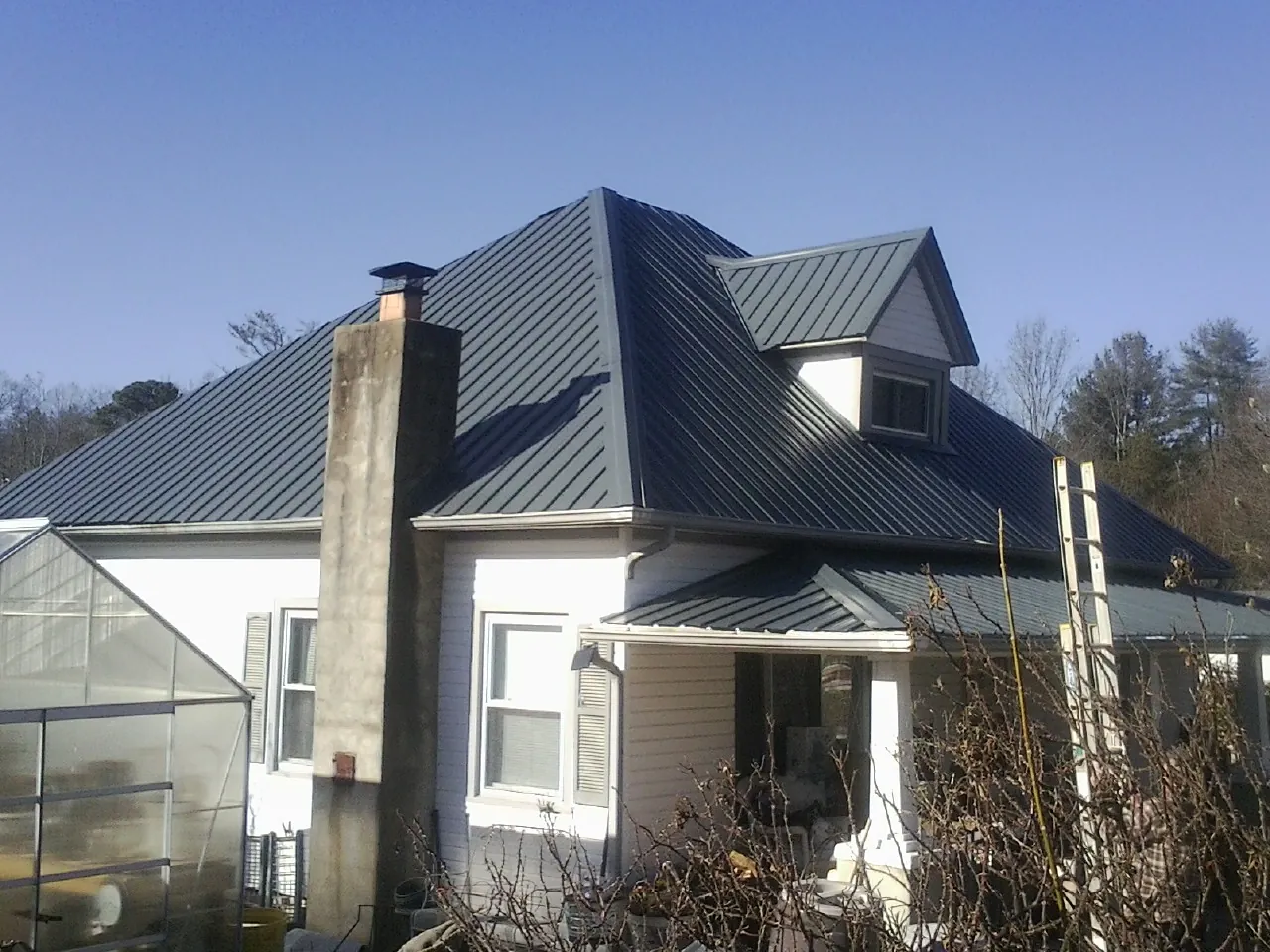 Dark blue standing seam metal roof on a white farmhouse with dormer — Slate & Tile Roof Repair by Roofing Brothers in Vermillion