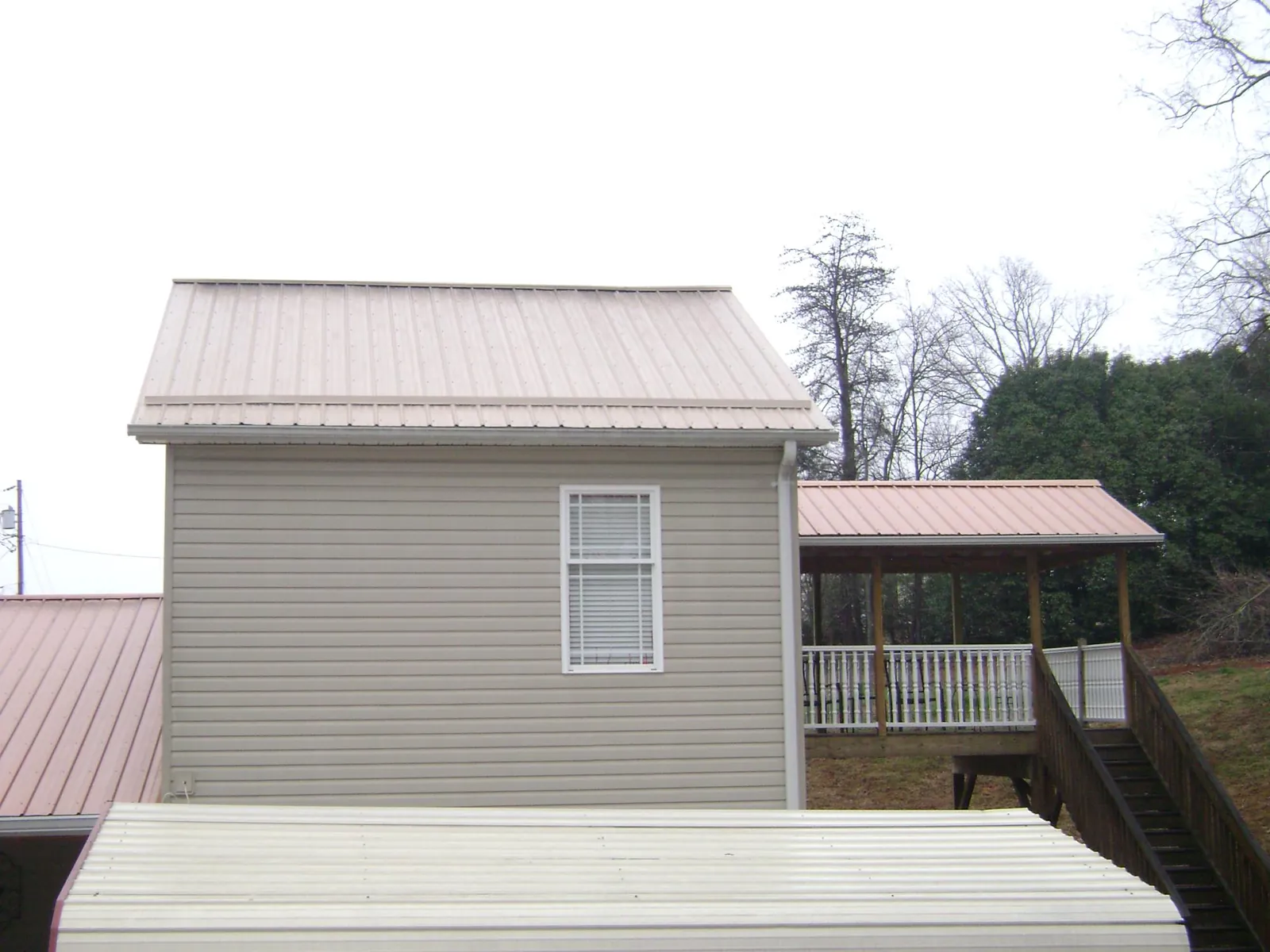 Tan metal roofs on a two story addition and attached porch, from a Roof Replacement job in Vermillion